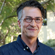 Picture of Jens Schmidt in a blue button down shirt and glasses with trees in the background